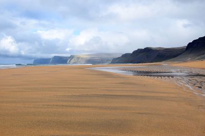 Scenic view of beach against cloudy sky