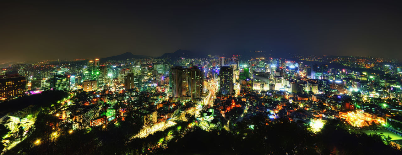 HIGH ANGLE VIEW OF ILLUMINATED CITY BUILDINGS AT NIGHT