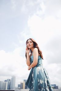 Young woman looking away against sky