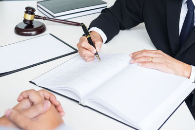 Midsection of man holding paper while sitting on table