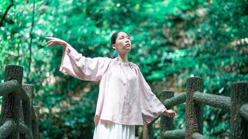 Woman with arms raised in the forest