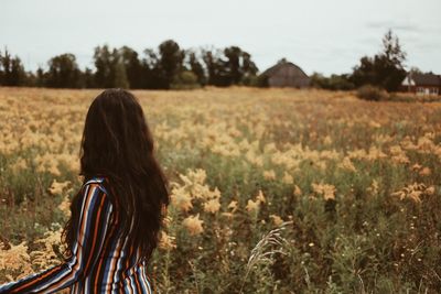 Rear view of young woman standing on flowering field
