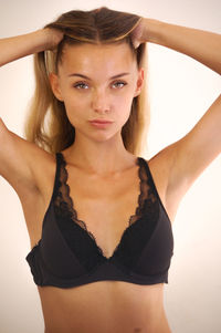 Portrait of young woman with arms raised standing against gray background