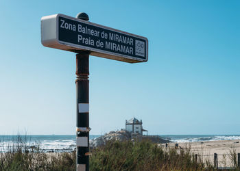 Information sign on beach against clear sky