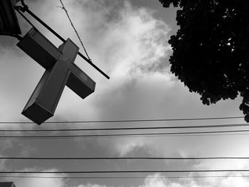 Low angle view of power lines against cloudy sky