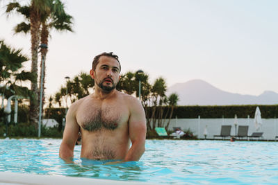 Portrait of young man standing in swimming pool