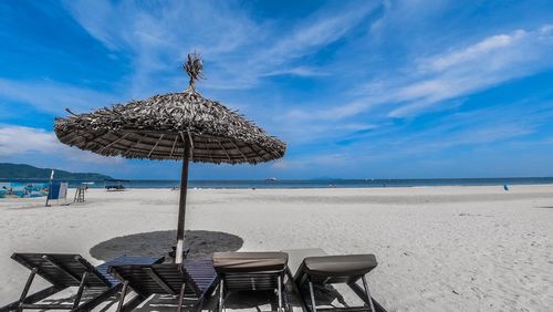 Chairs on beach by sea against sky