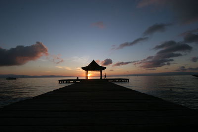 Pier over sea against sky during sunset