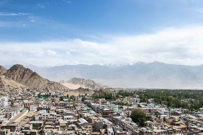 Aerial view of townscape and mountains against sky