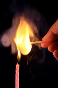 Close-up of hand holding lit match stick