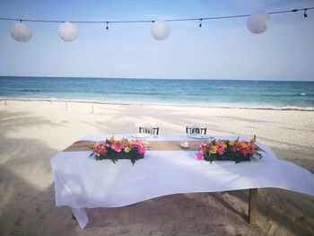 Flowers hanging on table by sea against sky