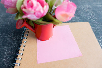 Pink flowers with paper and book on table