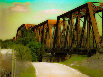 Footpath by bridge against sky