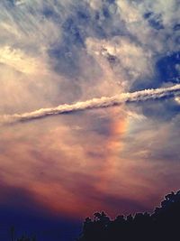 Low angle view of silhouette trees against dramatic sky