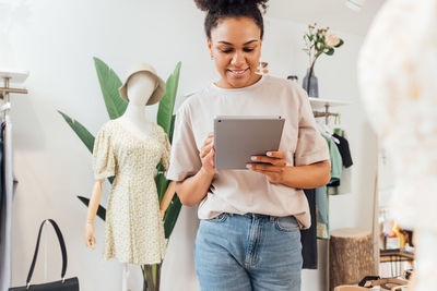 Smiling woman using digital tablet at boutique