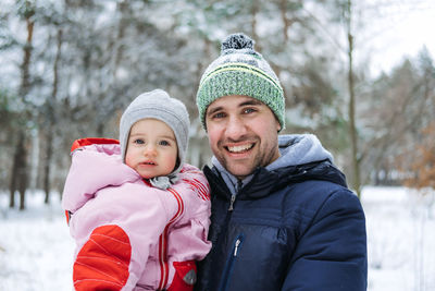 Outdoor portrait of young father and baby girl daughter in winter nature background. raising girls