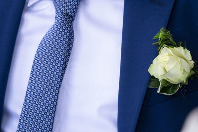 Detail of a blue formal dress for men, with white rose