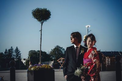 Happy wedding couple standing in city during sunny day