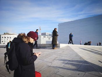 Rear view of people standing against buildings in city