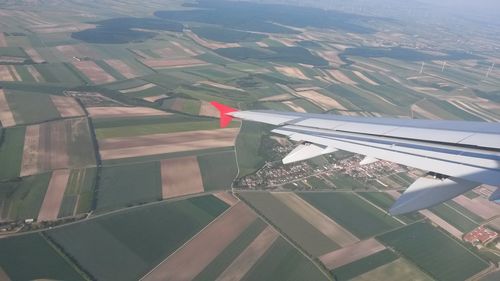 Aerial view of airplane wing over landscape against sky