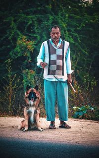 Portrait of man with dog standing against trees