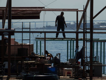 Worker standing on built structure against sea