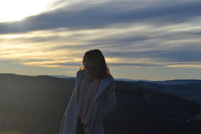 Portrait of young woman standing on mountain against sky