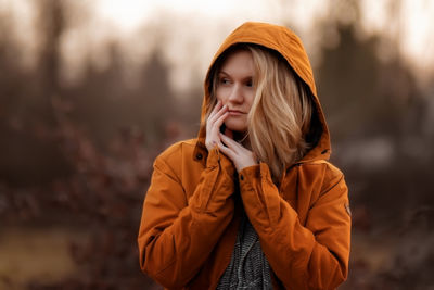 Young woman looking away while standing outdoors