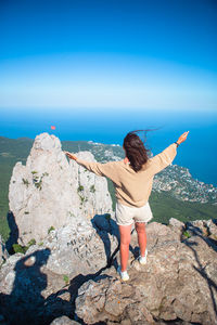 Rear view of woman looking at rock against sky