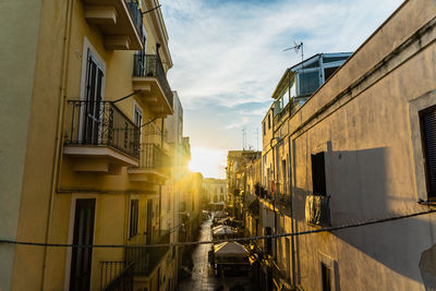 Street amidst buildings against sky during sunset