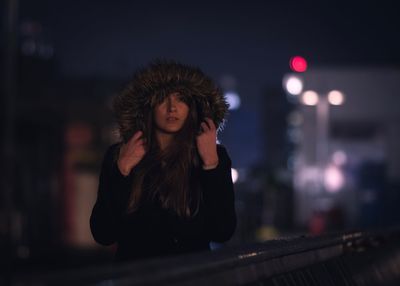 Young woman wearing fur hood at night