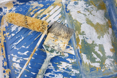High angle view of paintbrushes and paint roller on tray 