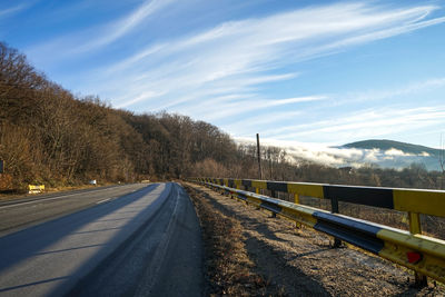 Road by trees against sky