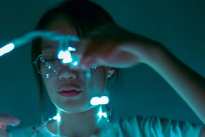 Young woman with illuminated string lights at home