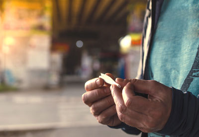 Midsection of man holding rolling joint