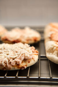 Small frozen pizza semi-finished product with tomato sause and cheese on grill prepared for baking