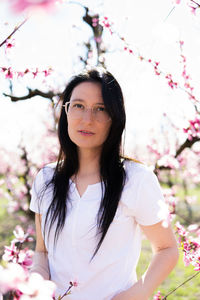 Portrait of sensual woman with glasses walking through a field of flowering peach trees in aitona