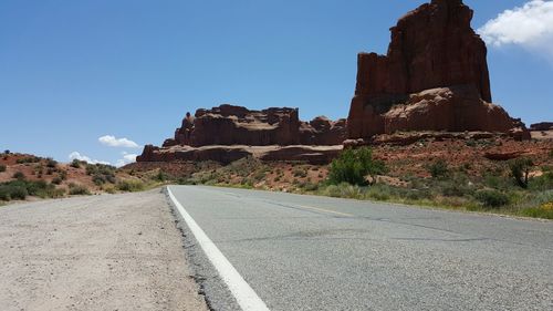 Road leading towards mountain against blue sky