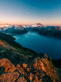 Scenic view of lake by mountains against sky during sunset