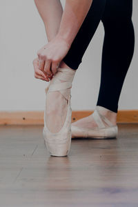 Low section of woman tying shoelace on hardwood floor