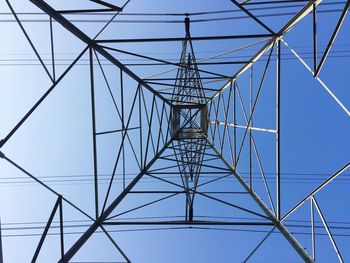 Low angle view of electricity pylon against clear blue sky