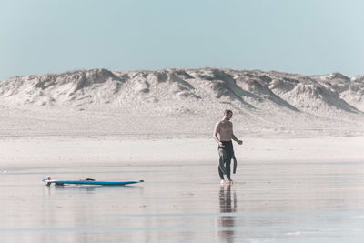 Young woman standing on beach against clear sky
