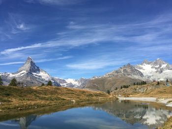 Scenic view of lake and mountains against blue sky