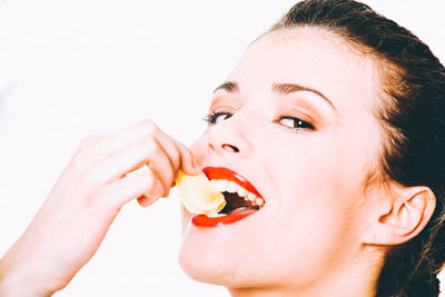 Portrait of woman eating food against white background