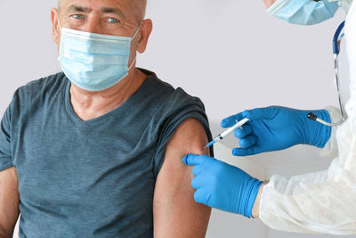 Doctor vaccinating senior man in clinic. older people vaccination. doctor giving covid19 vaccine 