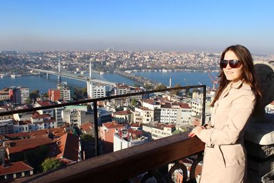 Smiling woman looking at city with golden horn metro bridge in background against clear blue sky