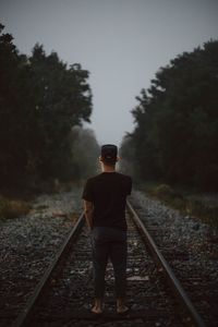 Rear view of man standing on railroad track