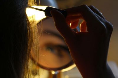 Close-up of woman applying make-up while looking in mirror