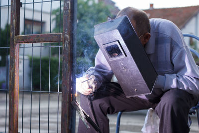 Welder old man welding a fence