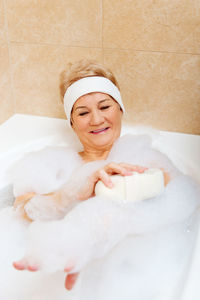 Smiling senior woman taking bath in bathroom at home